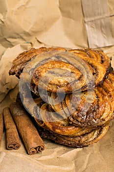 homemade sweet cinnamon rolls on paper bag with sticks of cinnamons