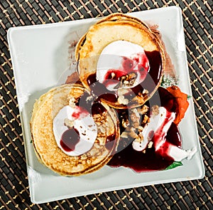 Homemade sweet pancakes with fruit jam, sour cream on a white plate. Breakfast with stack topped blueberry jam and