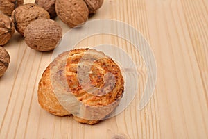 Homemade sweet roll of puff pastry with nuts and walnuts in shell on wooden background