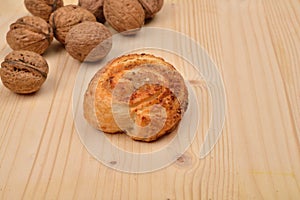 Homemade sweet roll of puff pastry with nuts and walnuts in shell on wooden background