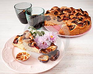 Homemade sweet round plum cake New York Times and cut n saucer with cups, glasses of tea, coffee on family holyday Breakfast or bi