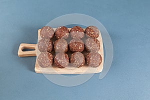 Homemade sweets on a wooden cutting board, top view. Energy balls are a healthy snack. Twelve smooth balls on a blue background,
