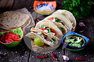 Homemade tacos with minced meat in tomato sauce with fresh tomatoes, cucumbers, chili and soft cheese. Mexican food.