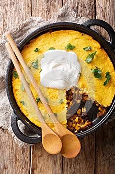 Homemade tamale pie casserole with corn and ground beef and cheese close-up in a frying pan. Vertical top view