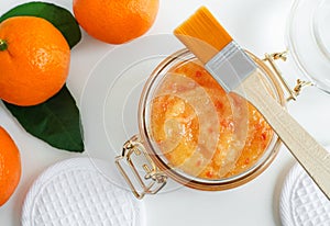 Homemade tangerine facial mask exfoliating sugar scrub in the glass jar. Mandarin orange DIY cosmetics and spa recipe. Top view