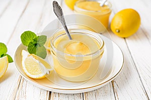 Homemade tangy lemon curd decorated with fresh fruit in a glass jars on rustic wooden background