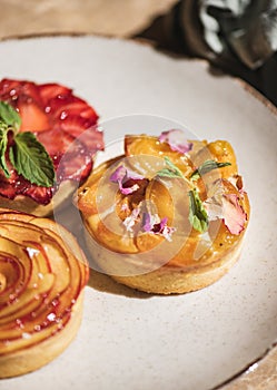 Homemade Tart desserts decorated with fresh strawberry, peach apricot, mint