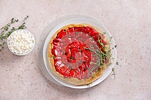 Homemade Tarte Tatin with bell red pepper and puff pastry served with thyme and soft cream cheese on a beige textured