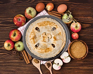 Homemade Tasty Apple Pie with Apples and Spices Wooden Background Top View Raw Apples Cinnamone Sticks photo