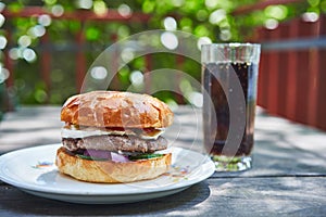 Homemade tasty and juicy beef burger served with cola drink on the vintage white porcelan plate.