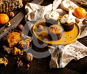 Homemade tasty sweet orange pumpkin muffins or cupcakes with white cream, lavender, zest, nuts