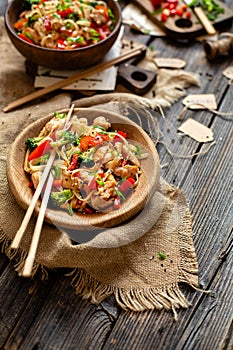 Homemade tasty wok noodles with fried chicken fillet, broccoli, red ball pepper, green onion, sesame