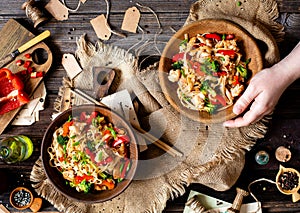 Homemade tasty wok noodles with fried chicken fillet, broccoli, red ball pepper, green onion, sesame