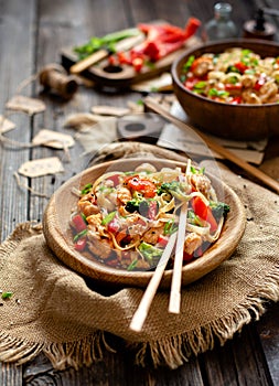 Homemade tasty wok noodles with fried chicken fillet, broccoli, red ball pepper, green onion, sesame