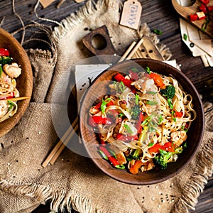 Homemade tasty wok noodles with fried chicken fillet, broccoli, red ball pepper, green onion, sesame