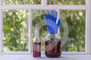 Homemade tincture of red cherry in a jar with a glove shaped shutter. Berry alcoholic drinks concept. Homemade red wine made from