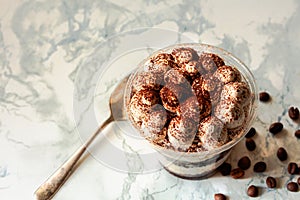 Homemade tiramisu, traditional Italian dessert in a plastic cup on a white marble background. Copy space. Top view