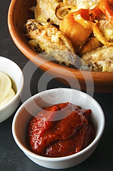 Homemade tomato paste for cooking lunch or dinner. Baked chicken wings on black background. Vertical view