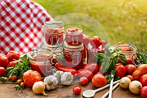 Homemade tomato preserves in glass jars and fresh tomatoes and herbs