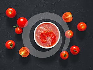 Homemade tomato sauce made from fresh ripe tomatoes in white bowl on black background. Vegetarian food. Top view