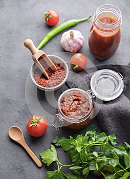 Homemade tomato sauce for pizza or pasta in a jar on a dark background with fresh vegetables, herbs and spicy. The concept of