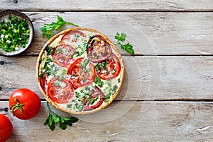 Homemade tomatoes and green onion pie quiche on old wooden table