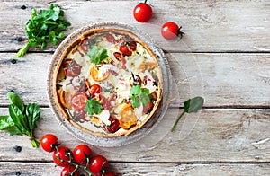 Homemade tomatoes and spinach pie quiche on natural wooden table