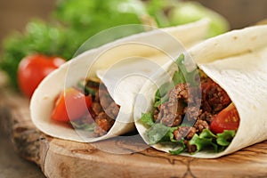 Homemade tortilla with beef, frillice and vegetables on wooden board