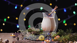 Homemade traditional Christmas eggnog drink in glass with ground nutmeg and cinnamon decorating with christmas tree and