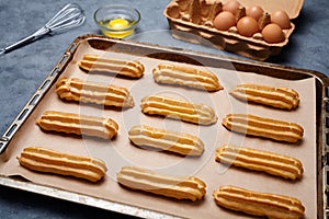 Homemade traditional eclairs or profiterole preparing recipe on baking sheet