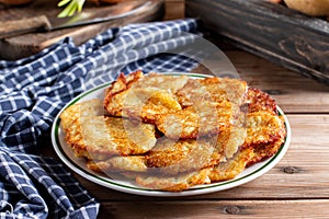 Homemade traditional fried potato pancakes latke for Hanukkah served with sour cream and greens on dish. Rustic wooden