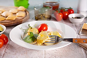 Homemade traditional italian ravioli pasta with basil and tomato cherry vegetables on the table