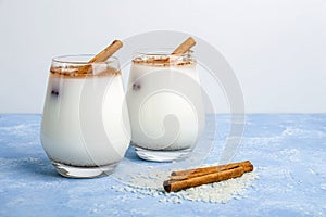 Homemade traditional mexican or spanish cool rice Horchata in a glass on blue background. Fresh cool drink or cocktail made from