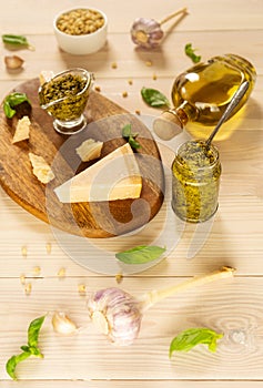 Homemade traditional pesto sauce: basil, olive oil, parmesan, garlic, pine nuts. Ingredients lay on brown wooden board.