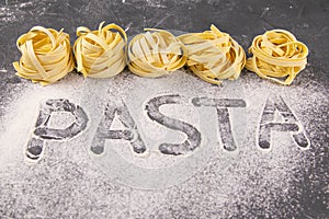 Homemade uncooked pasta tagliatelle on black background. Making fresh italian tagliatelle . The word `pasta` from flour. Banner