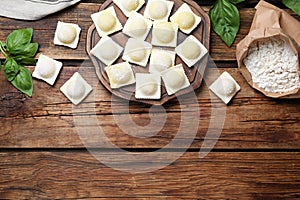 Homemade uncooked ravioli on wooden table, flat lay. Space for text