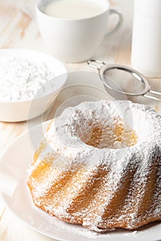 Homemade vanilla bundt cake on white wooden background