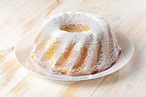 Homemade vanilla bundt cake on white wooden background