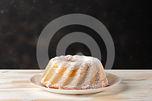 Homemade vanilla bundt cake on white wooden background