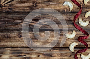 Homemade vanilla cookies and red natural ribbon on rustic wooden background.