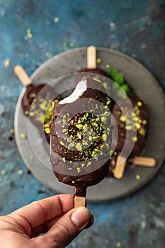 Homemade vanilla ice cream with chocolate glaze and pistachios