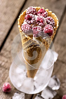 Homemade Vanilla Ice Cream in Waffle Cone with Frozen Raspberry Lying on on Rustic Wooden Background Tasty Ice Cream Summer