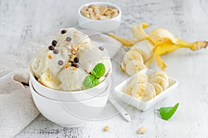 Homemade vegan banana ice cream in a bowl with peanuts and chocolate on a wooden background. Healthy dessert. photo