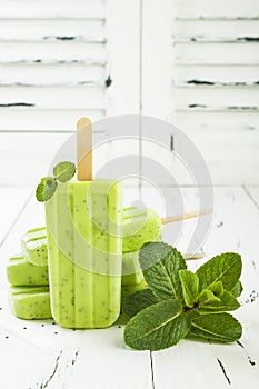 Homemade vegan green tea matcha mint coconut milk popsicles with chia seeds on rustic white wooden background