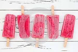 Homemade vegan raspberry coconut milk popsicles - ice pops - paletas with chia seeds on rustic white wooden background. photo