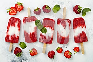 Homemade vegan strawberry coconut milk popsicles - ice pops - paletas on rustic white background.