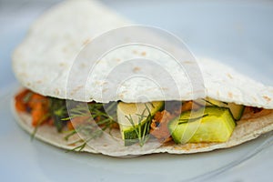 Homemade vegan tortilla wrap with black beans, cucumber, squash, bell peppers, sweet potatoes, avocado mash and dill. Extreme clos