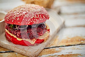 Homemade vegetable beetroot burgers. Red colored sesame bun. Served with goat cheese, feta