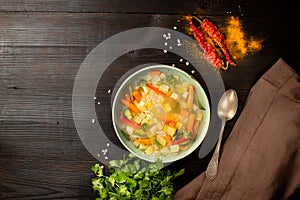 Homemade vegetable soup, overhead view on a dark wooden background