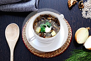 Homemade vegetarian mushroom soup with pearl barley and vegetables in a white Cup with two handles